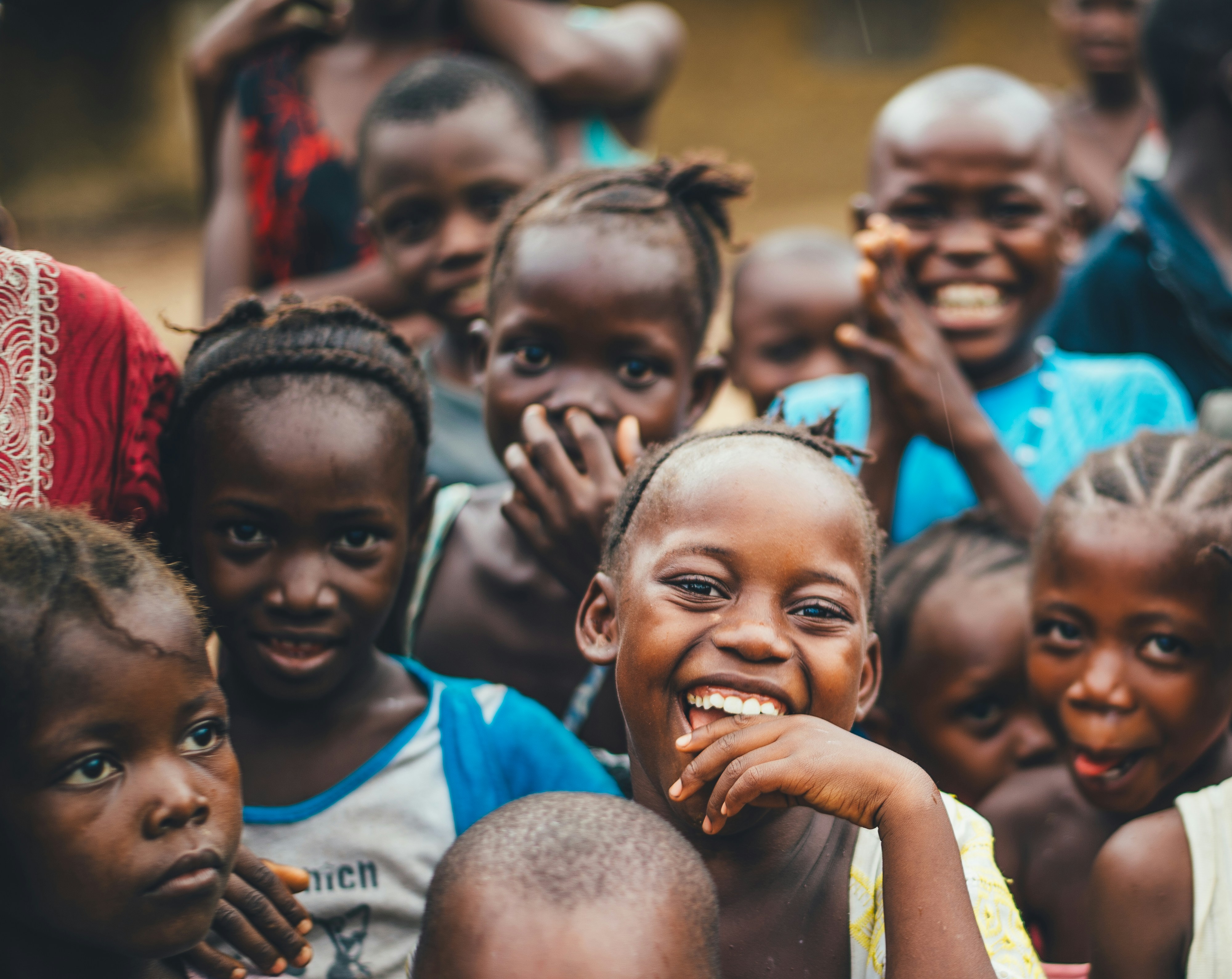 Joyful children of a Nigerian community gathering at sunset, representing the people SONRU ISELE CHARITY FOUNDATION serves